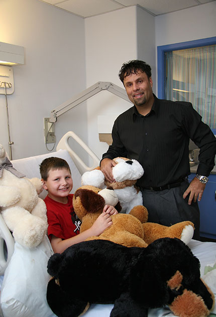 George Lou Karmiris presents stuffed animals to kids in hospital bed at BGH.