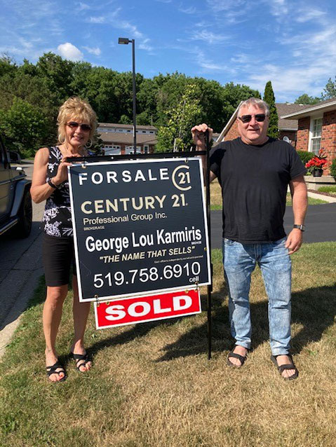 Clients of George Lou Karmiris standing with the sold sign.