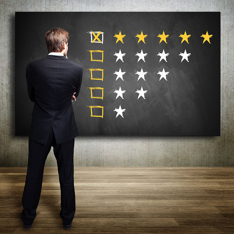 Man standing in front of a blackboard with multiple star ratings from one to five.