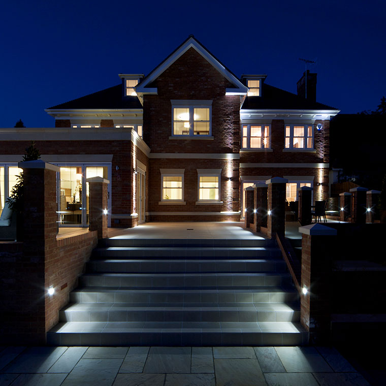 Night photo of front sidewalk leading up to a beautifully lighted upscale home.